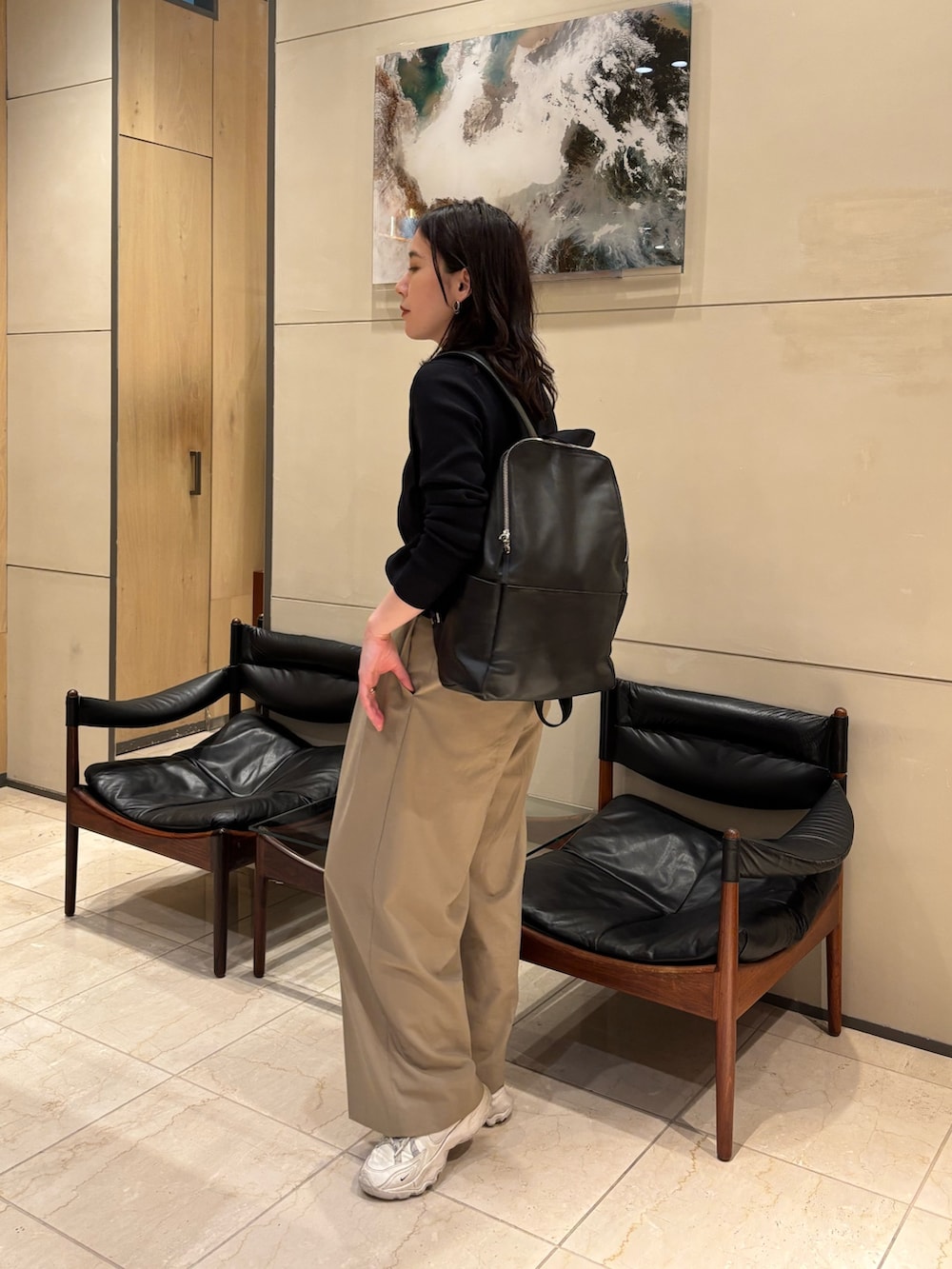 ブラック系のニット/セーター、ベージュ系のその他パンツ、ブラック系のバックパック/リュックを着用したレディースの春コーディネートの3枚目の写真
