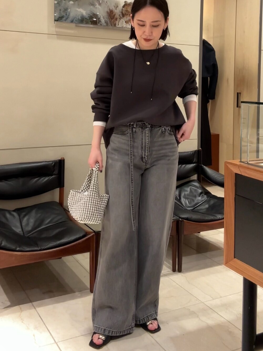 ブラウン系のTシャツ/カットソー、グレー系のデニムパンツ、ブラック系のサンダルを着用したレディースの春コーディネートの2枚目の写真