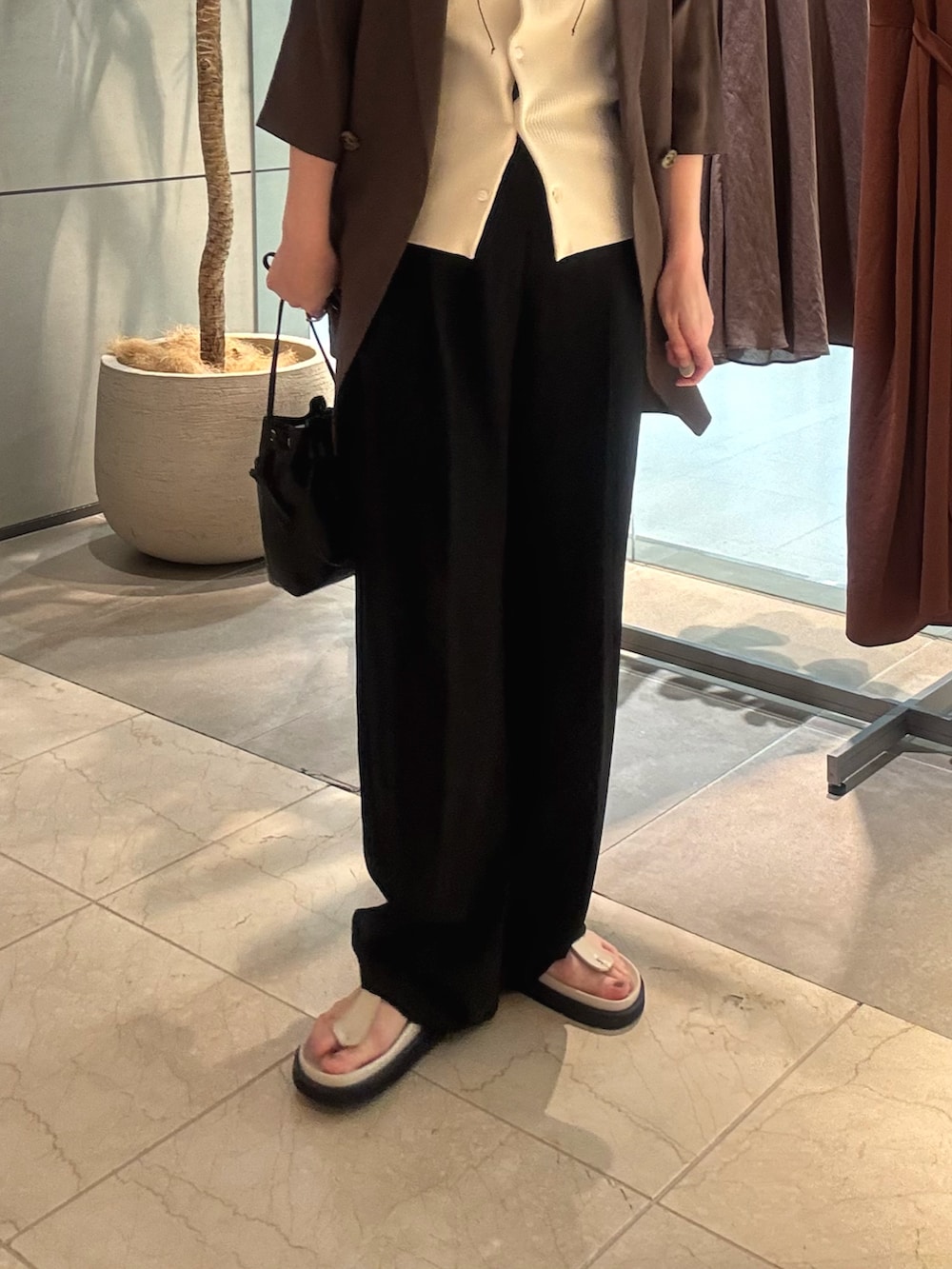 ブラウン系のテーラードジャケット、ベージュ系のニット/セーター、ブラック系のその他パンツを着用したレディースの夏コーディネートの4枚目の写真