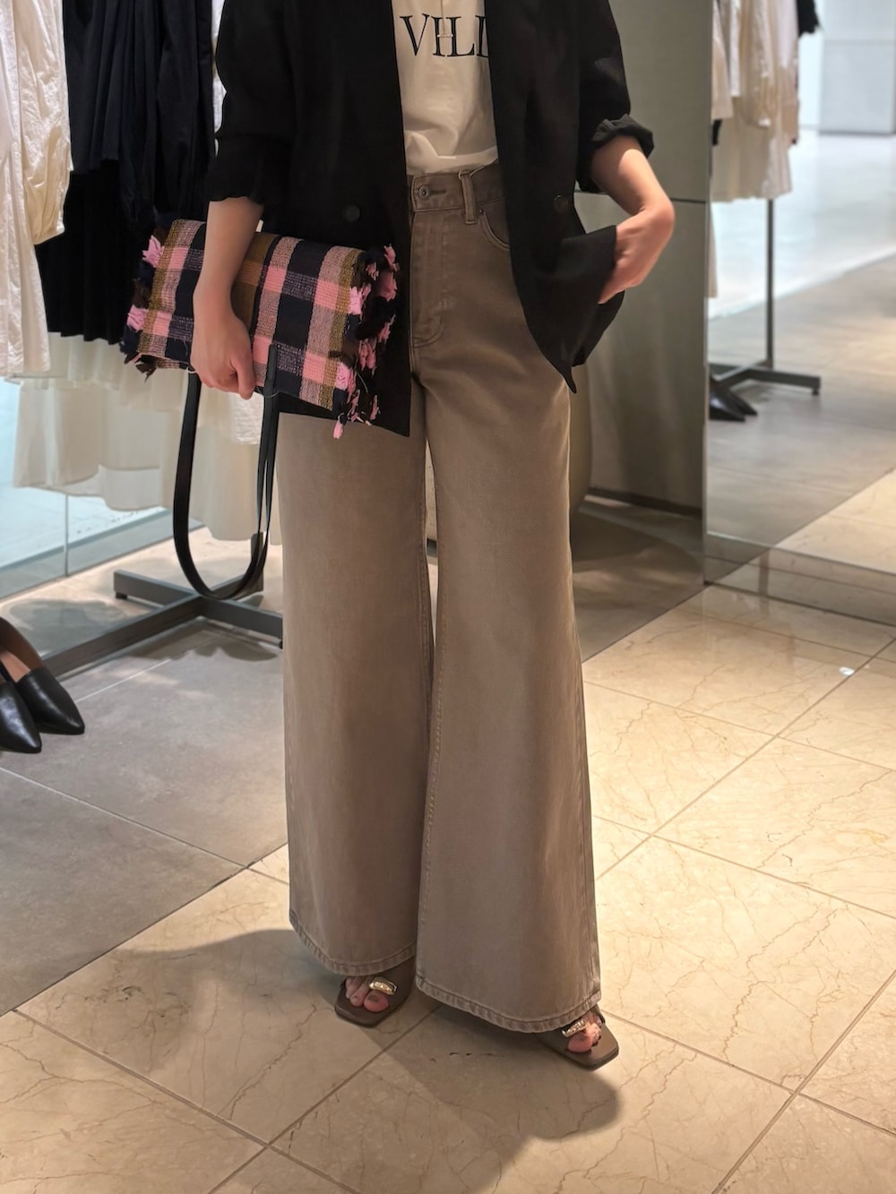 ブラック系のテーラードジャケット、ブラウン系のデニムパンツ、ブラウン系のサンダルを着用したレディースの春コーディネートの2枚目の写真