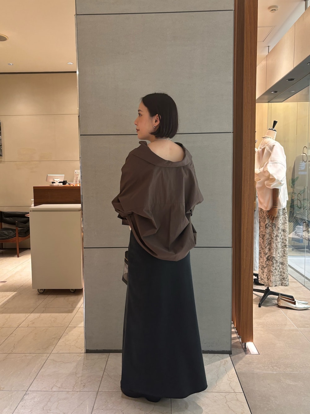 ブラウン系のシャツ/ブラウス、ブラック系のスカート、ブラック系のブーツを着用したレディースの春コーディネートの2枚目の写真