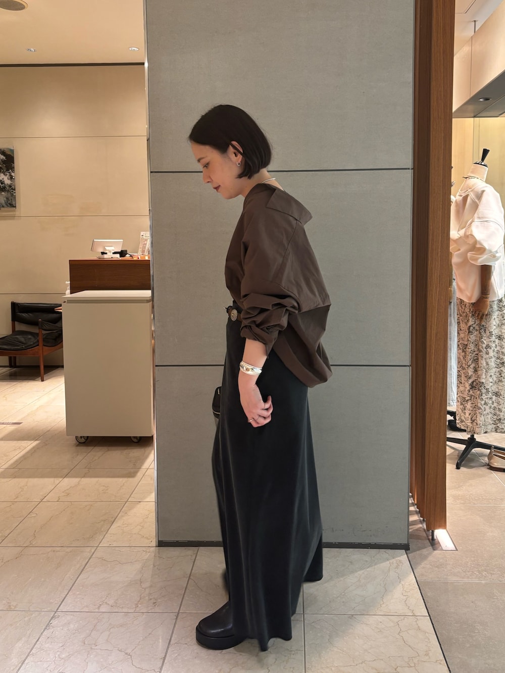 ブラウン系のシャツ/ブラウス、ブラック系のスカート、ブラック系のブーツを着用したレディースの春コーディネートの3枚目の写真