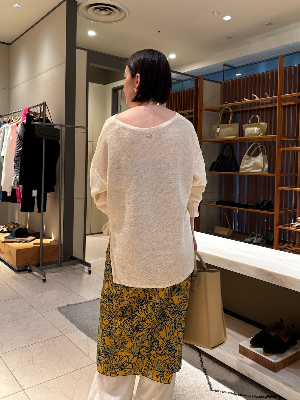 ホワイト系のニット/セーター、ホワイト系のその他パンツ、ベージュ系のトートバッグを着用したレディースの春コーディネートの3枚目の写真