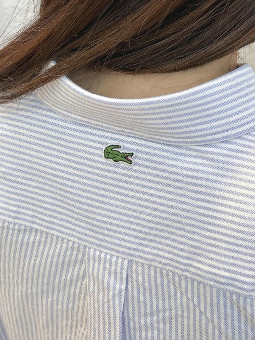 「ダウン、シャツ、キャンバスシューズ、チェーンバッグ、ストライプシャツ」｜「LACOSTEのタイムラインクロックストライプオックスフォードシャツ（シャツ/ブラウス、ブルー系）」を使った、momoさん（レディース・166cm）の春コーディネートの6枚目の写真