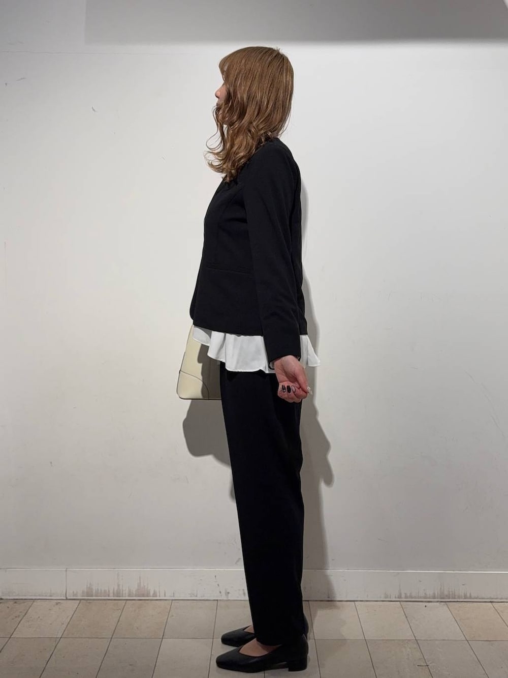 ブラック系のパンプス、ベージュ系のボストンバッグ、ブラック系のセットアップを着用したレディースの冬コーディネートの2枚目の写真