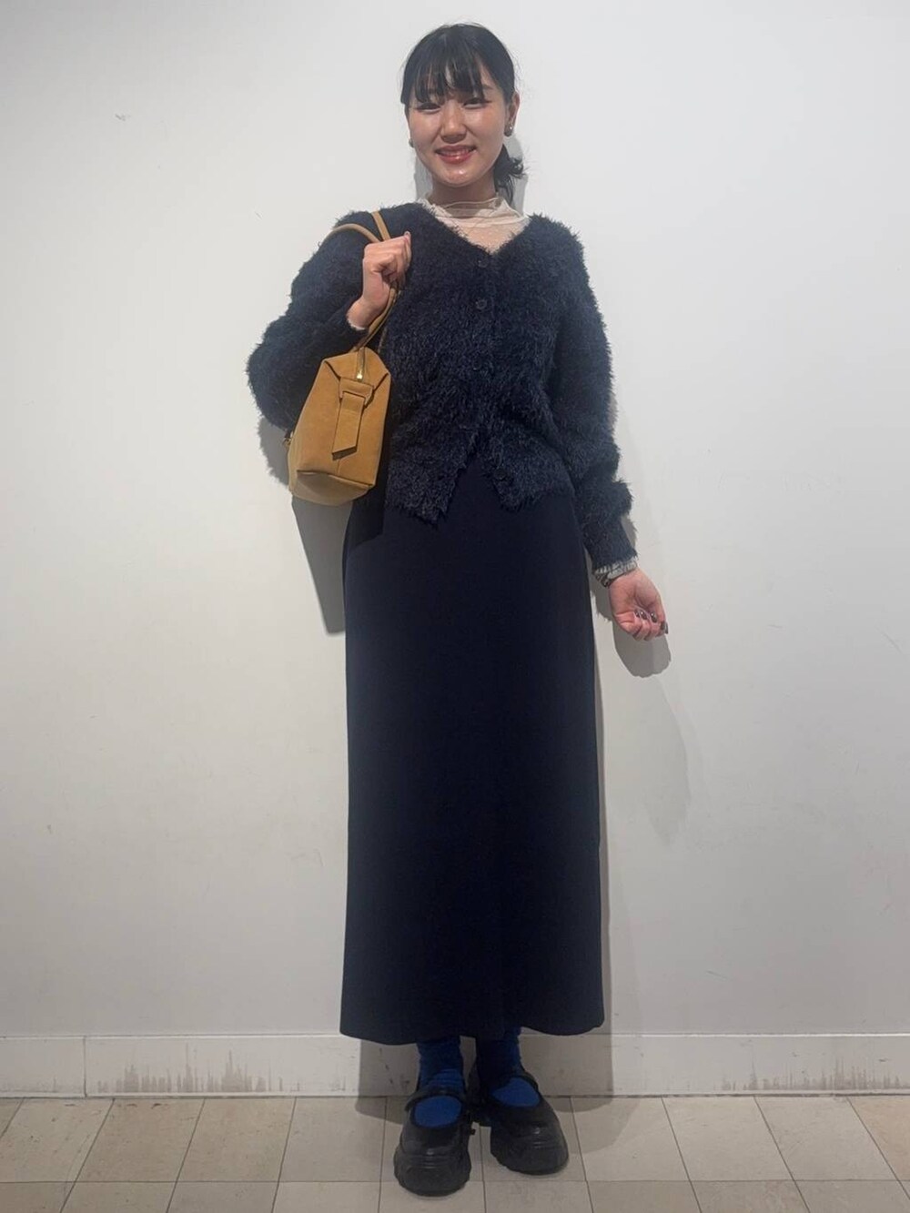 ブラック系のスニーカー、ベージュ系のボストンバッグ、ブルー系のワンピースを着用したレディースの秋コーディネートの4枚目の写真