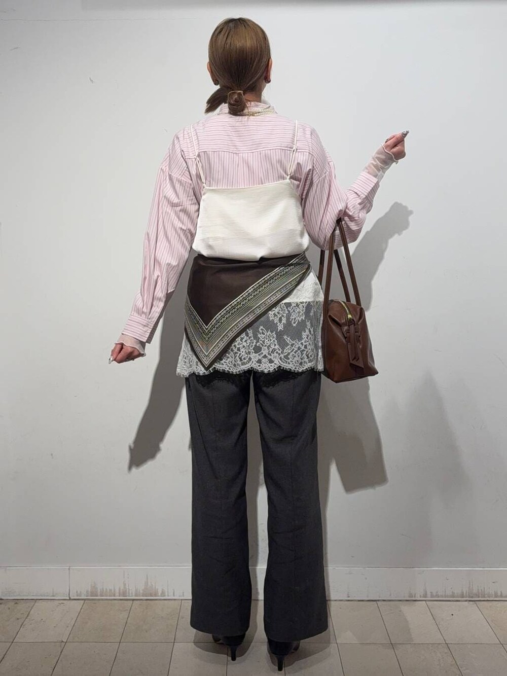 ブラウン系のボストンバッグ、ピンク系のシャツ/ブラウス、ホワイト系のTシャツ/カットソーを着用したレディースの冬コーディネートの3枚目の写真