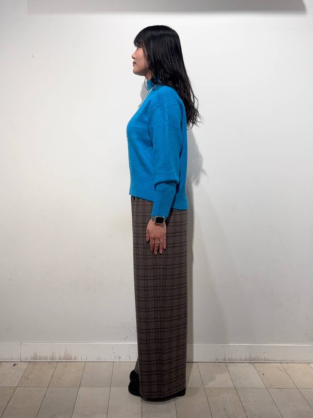 ブルー系のニット/セーター、ブラウン系のその他パンツ、シルバー系のネックレスを着用したレディースの冬コーディネートの2枚目の写真