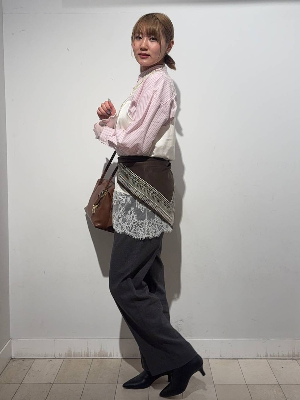 ブラウン系のボストンバッグ、ピンク系のシャツ/ブラウス、ホワイト系のTシャツ/カットソーを着用したレディースの冬コーディネートの2枚目の写真