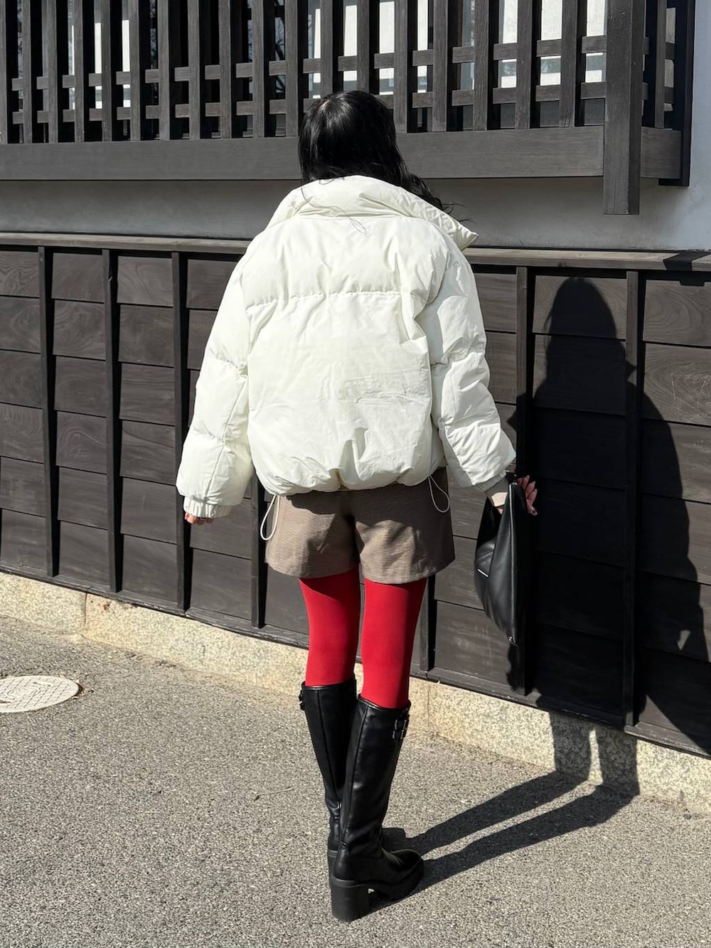 ホワイト系のブルゾン、ブラック系のブーツ、ベージュ系のニット/セーターを着用したレディースの冬コーディネートの2枚目の写真