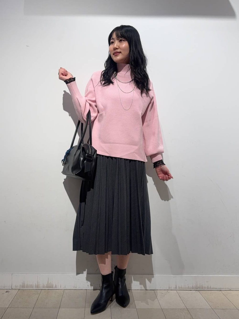 ブラック系のボストンバッグ、ブルー系のチェスターコート、ピンク系のニット/セーターを着用したレディースの冬コーディネートの2枚目の写真