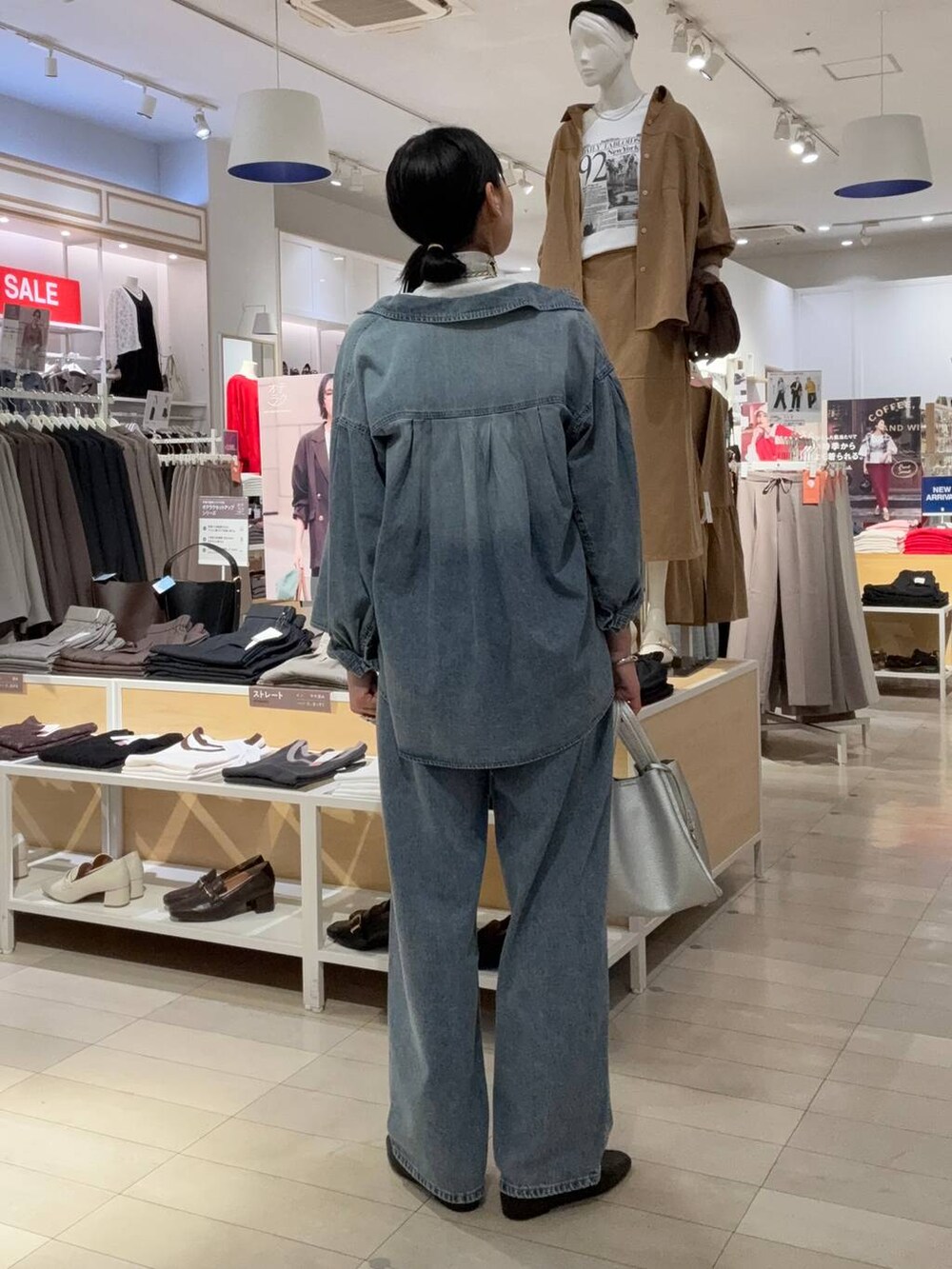 ブラック系のパンプス、ブルー系のデニムパンツ、シルバー系のトートバッグを着用したレディースの秋コーディネートの3枚目の写真