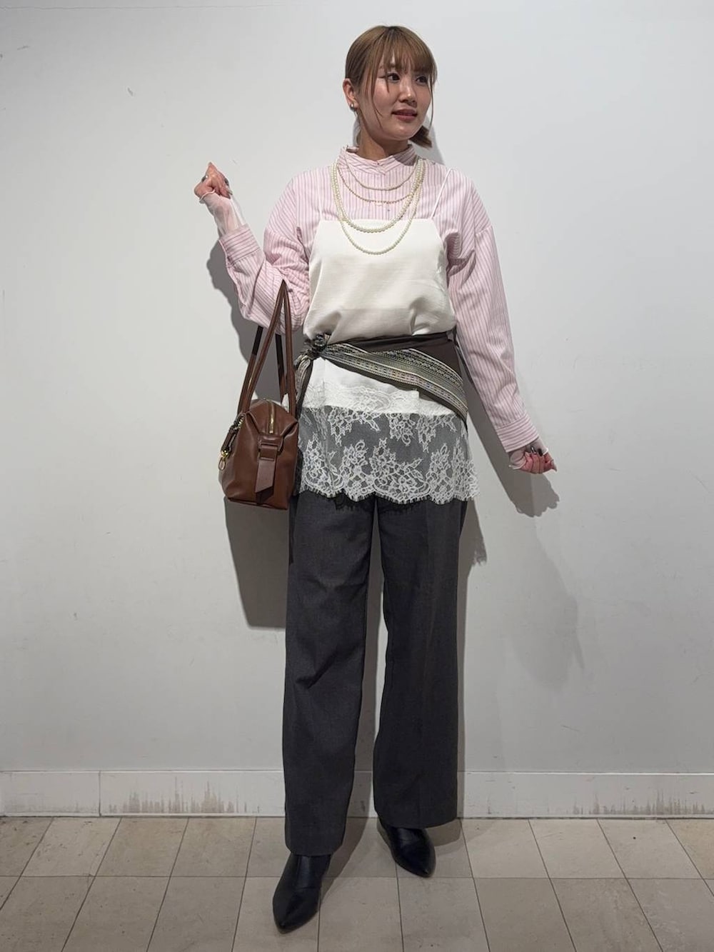 ブラウン系のボストンバッグ、ピンク系のシャツ/ブラウス、ホワイト系のTシャツ/カットソーを着用したレディースの冬コーディネートの4枚目の写真