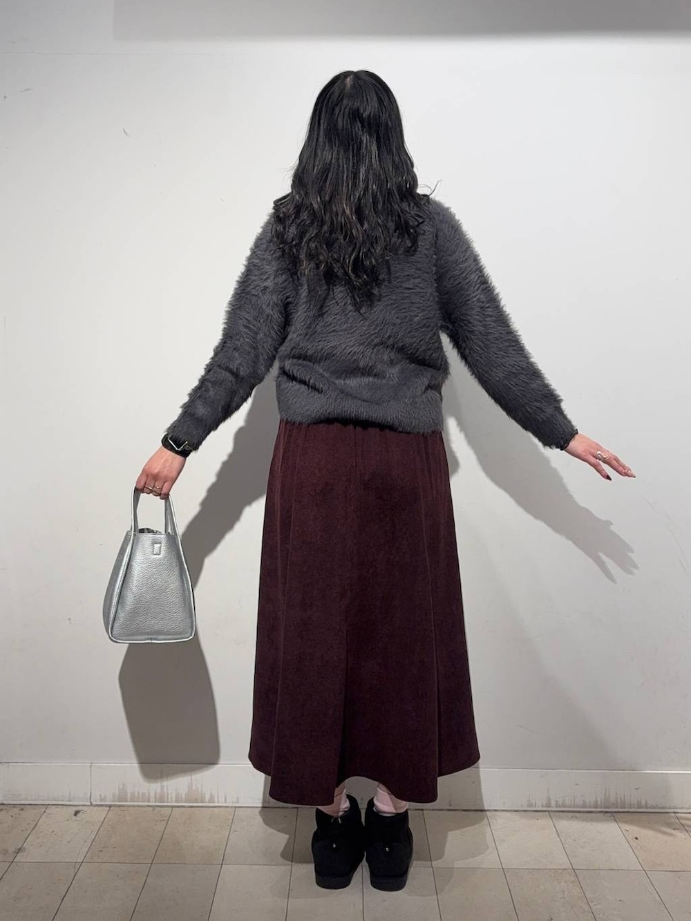 ブラック系のステンカラーコート、レッド系のスカート、ブラック系のTシャツ/カットソーを着用したレディースの冬コーディネートの5枚目の写真