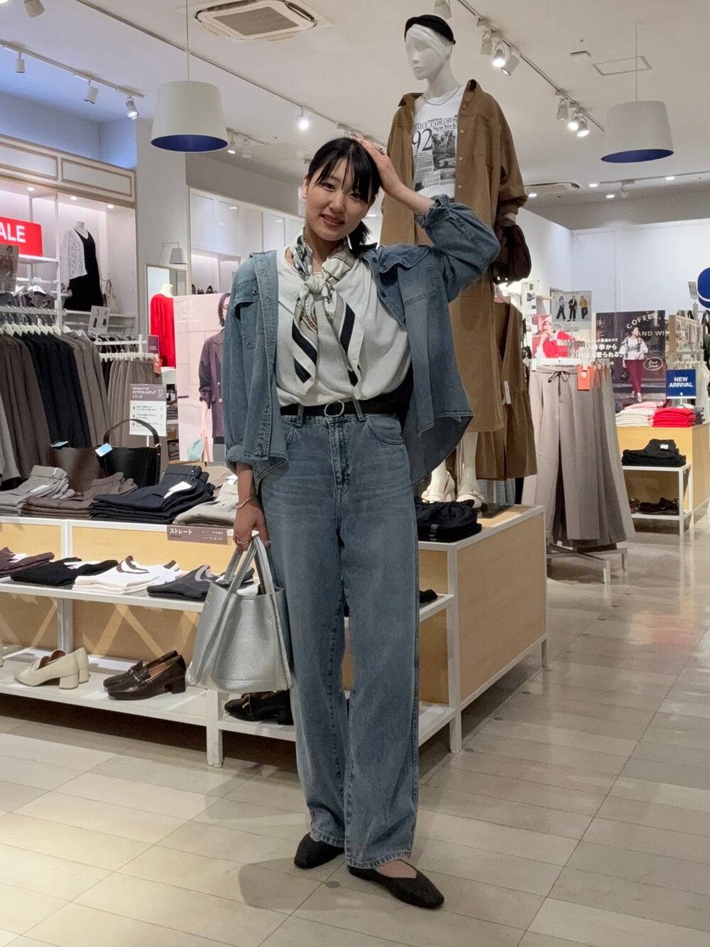 ブラック系のパンプス、ブルー系のデニムパンツ、シルバー系のトートバッグを着用したレディースの秋コーディネートの2枚目の写真