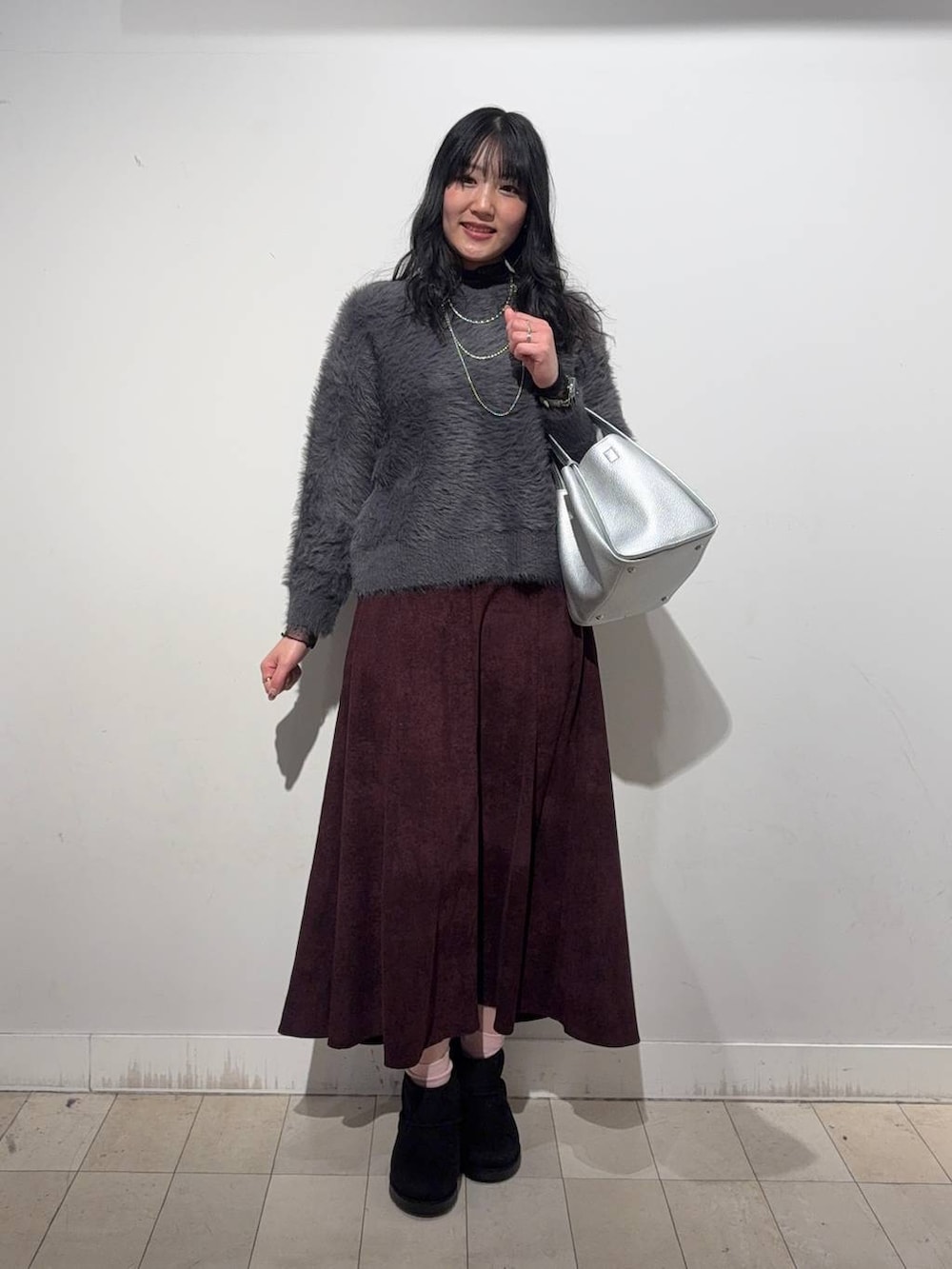 ブラック系のステンカラーコート、レッド系のスカート、ブラック系のTシャツ/カットソーを着用したレディースの冬コーディネートの2枚目の写真