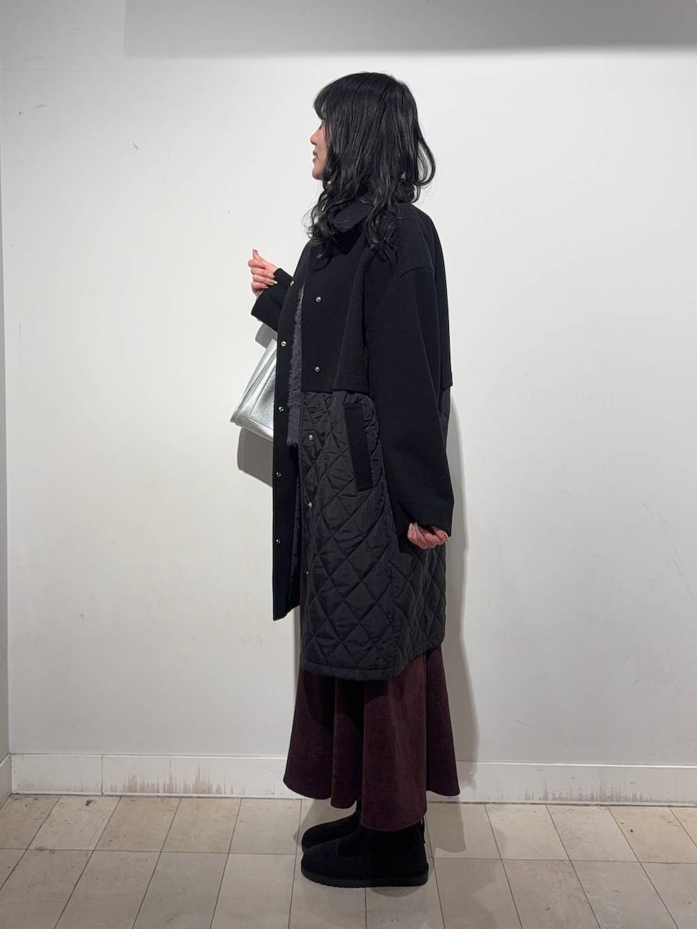 ブラック系のステンカラーコート、レッド系のスカート、ブラック系のTシャツ/カットソーを着用したレディースの冬コーディネートの3枚目の写真