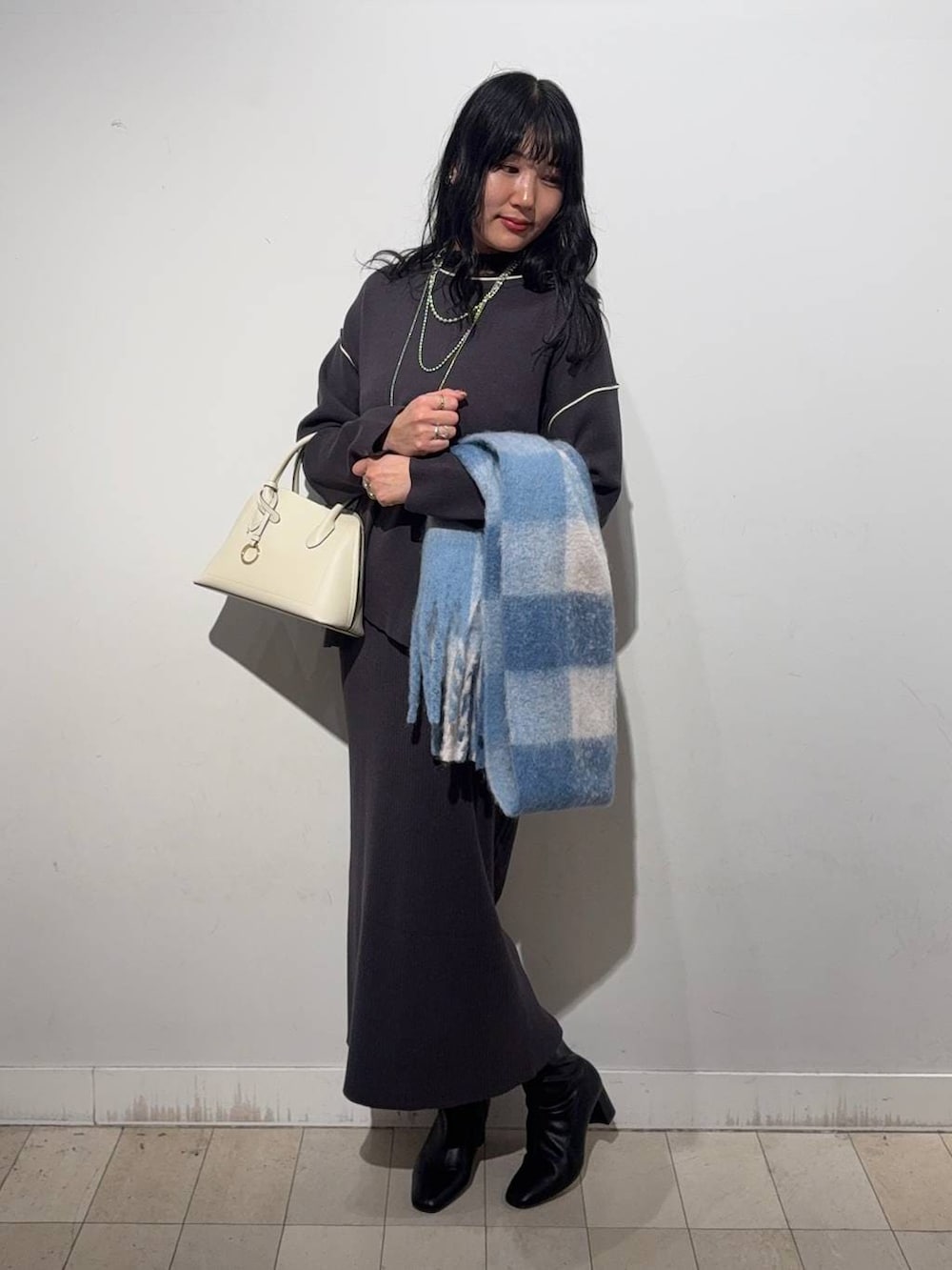 ホワイト系のショルダーバッグ、グレー系のワンピース、ブラック系のブーツを着用したレディースの秋コーディネートの5枚目の写真