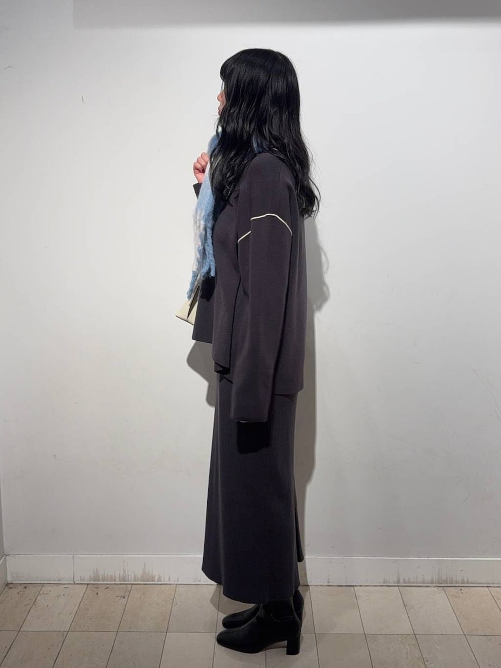 ホワイト系のショルダーバッグ、グレー系のワンピース、ブラック系のブーツを着用したレディースの秋コーディネートの2枚目の写真