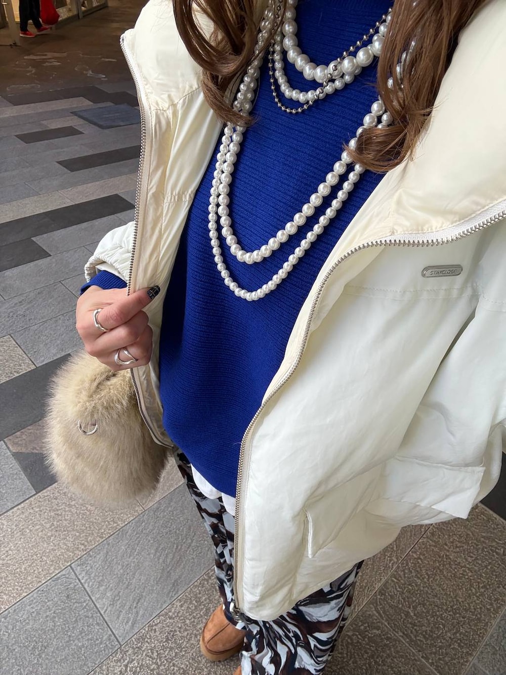 ホワイト系のブルゾン、イエロー系のブーツ、ホワイト系のTシャツ/カットソーを着用したレディースの冬コーディネートの2枚目の写真