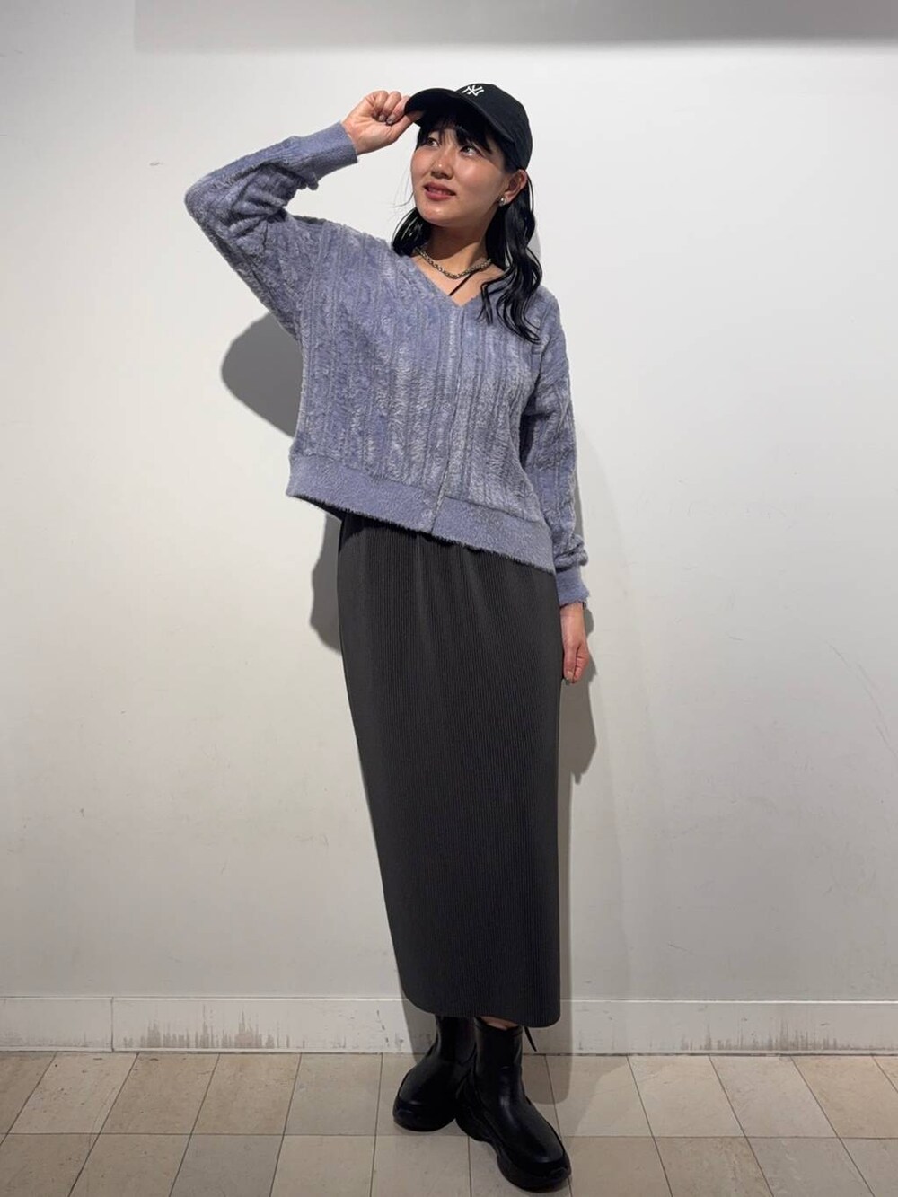 グレー系のスカート、ブラック系のブーツ、パープル系のカーディガン/ボレロを着用したレディースの秋コーディネートの2枚目の写真