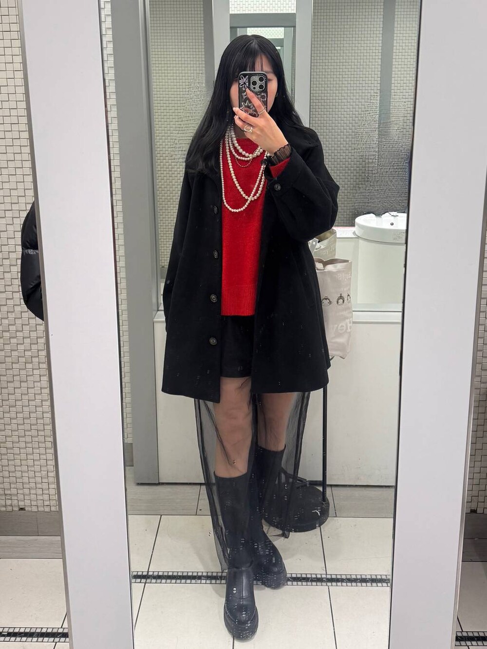 レッド系のニット/セーター、ブラック系のTシャツ/カットソー、ブラック系のその他パンツを着用したレディースの冬コーディネートの2枚目の写真