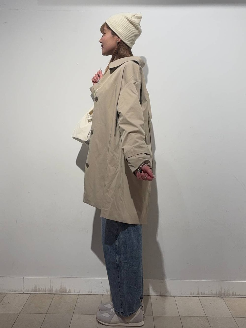 ベージュ系のスニーカー、ホワイト系のTシャツ/カットソー、ベージュ系のステンカラーコートを着用したレディースの冬コーディネートの2枚目の写真