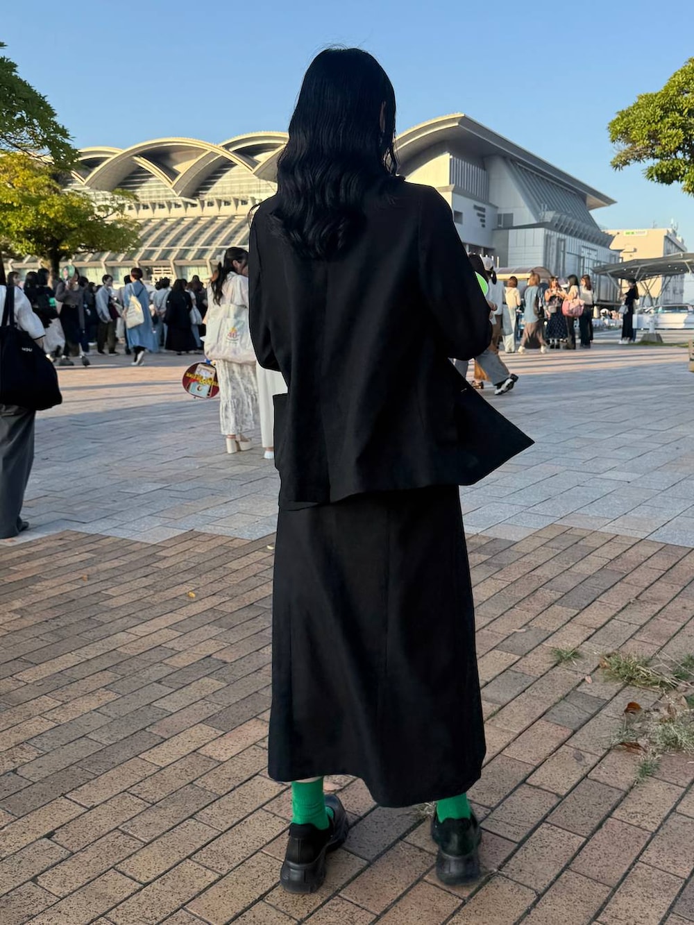 ブラック系のスニーカー、ブラック系のテーラードジャケット、シルバー系のネックレスを着用したレディースの秋コーディネートの3枚目の写真