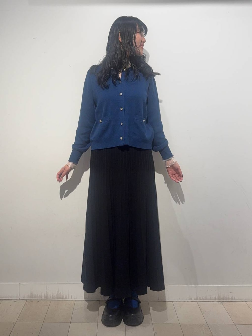 ブラック系のスニーカー、ブルー系のカーディガン/ボレロ、ブラック系のスカートを着用したレディースの秋コーディネートの3枚目の写真