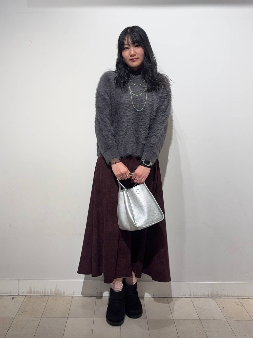 ブラック系のステンカラーコート、レッド系のスカート、ブラック系のTシャツ/カットソーを着用したレディースの冬コーディネートの4枚目の写真