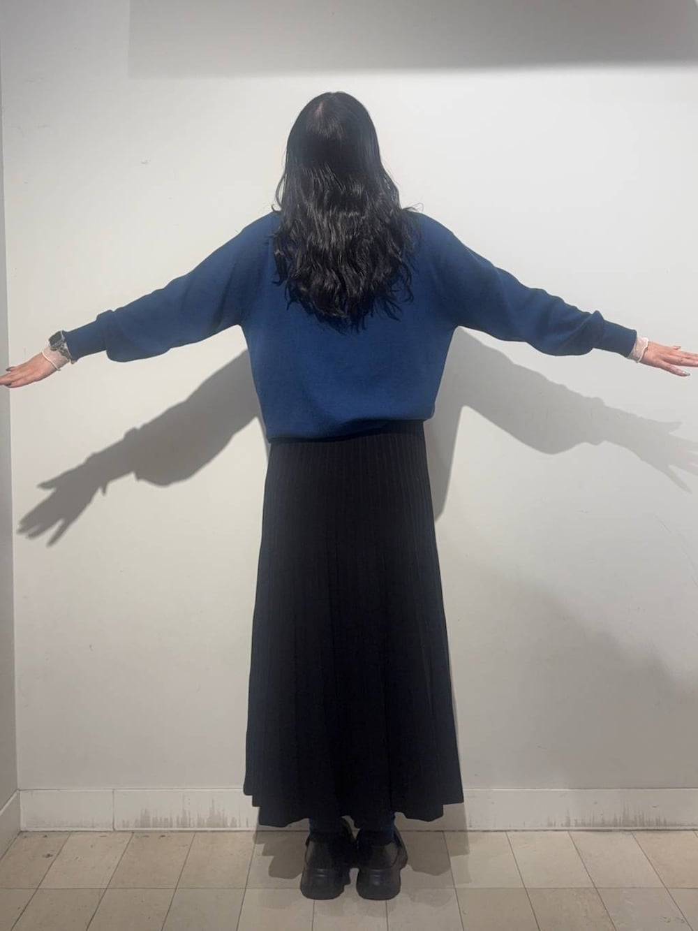 ブラック系のスニーカー、ブルー系のカーディガン/ボレロ、ブラック系のスカートを着用したレディースの秋コーディネートの2枚目の写真