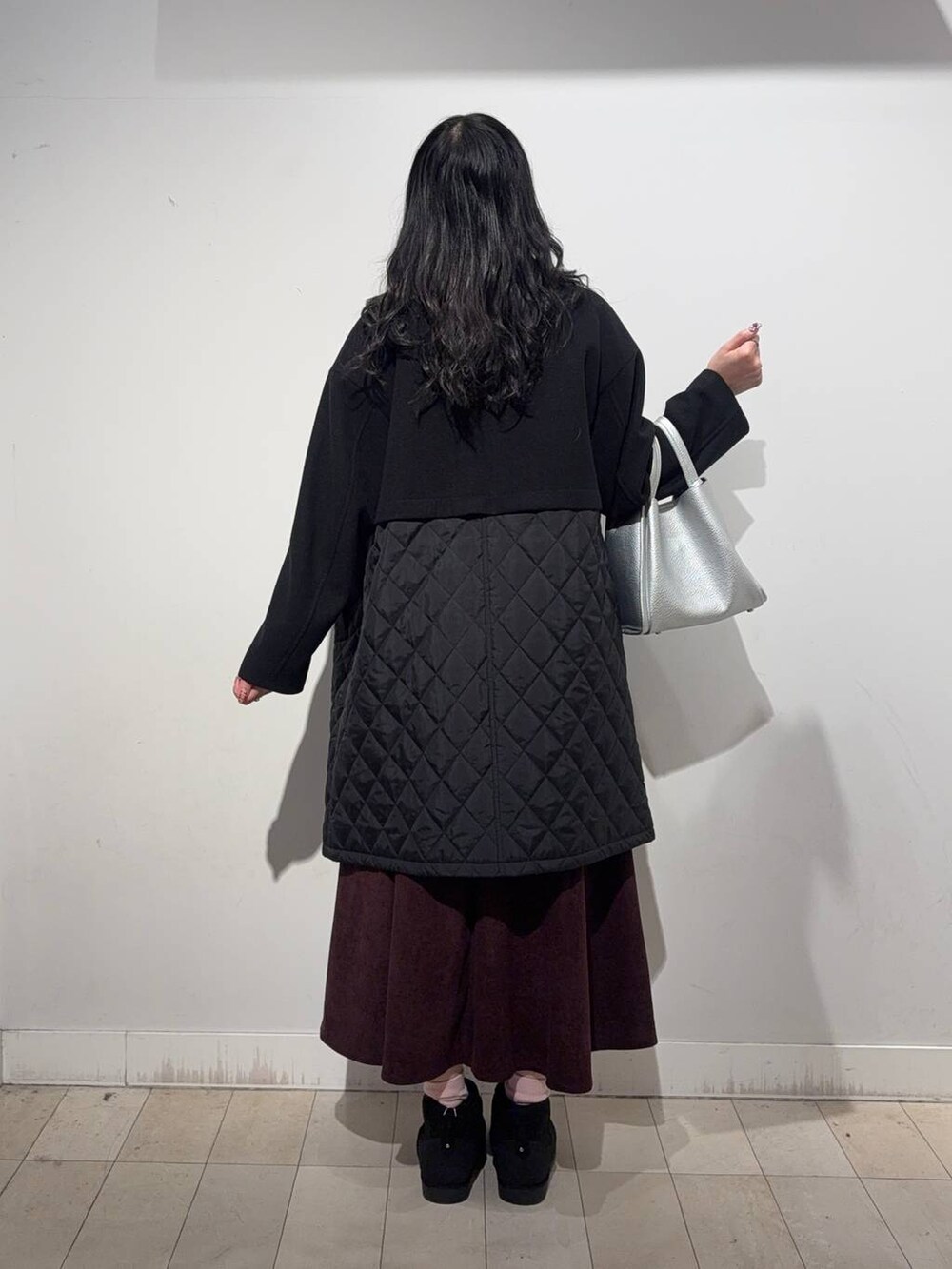 ブラック系のステンカラーコート、レッド系のスカート、ブラック系のTシャツ/カットソーを着用したレディースの冬コーディネートの6枚目の写真