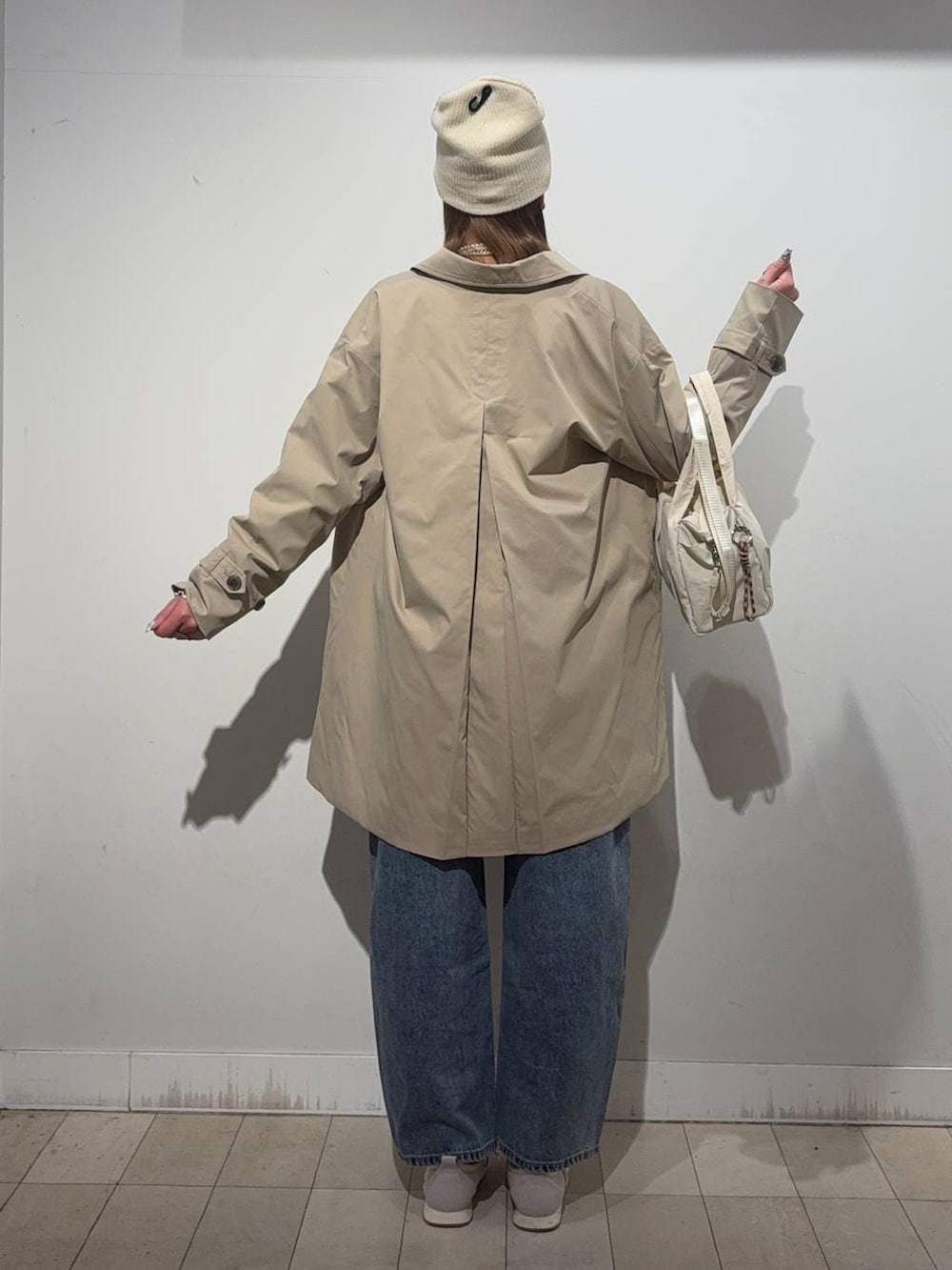 ベージュ系のスニーカー、ホワイト系のTシャツ/カットソー、ベージュ系のステンカラーコートを着用したレディースの冬コーディネートの3枚目の写真