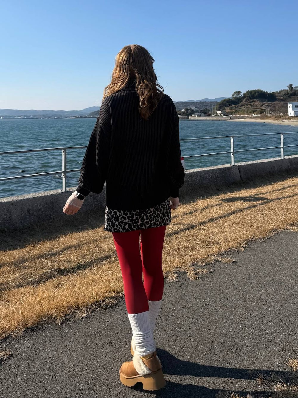 イエロー系のブーツ、ブラック系のニット/セーター、ブラウン系のスカートを着用したレディースの冬コーディネートの2枚目の写真