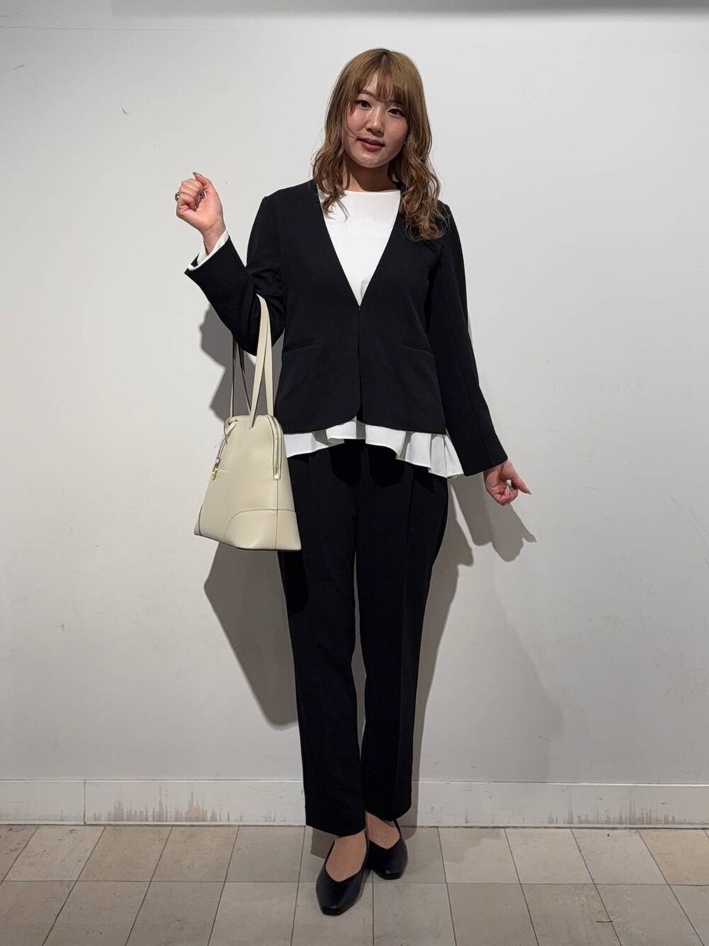 ブラック系のパンプス、ベージュ系のボストンバッグ、ブラック系のセットアップを着用したレディースの冬コーディネートの4枚目の写真