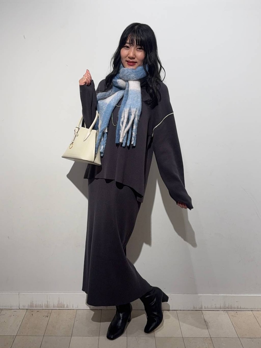 ホワイト系のショルダーバッグ、グレー系のワンピース、ブラック系のブーツを着用したレディースの秋コーディネートの3枚目の写真