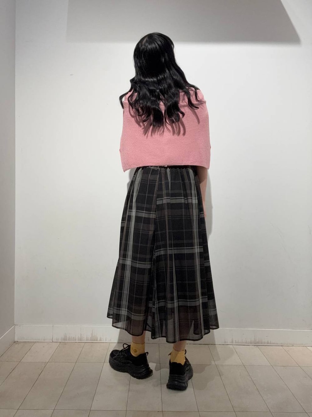 ブラック系のスカート、ブラック系のスニーカー、ピンク系のカーディガン/ボレロを着用したレディースの秋コーディネートの3枚目の写真