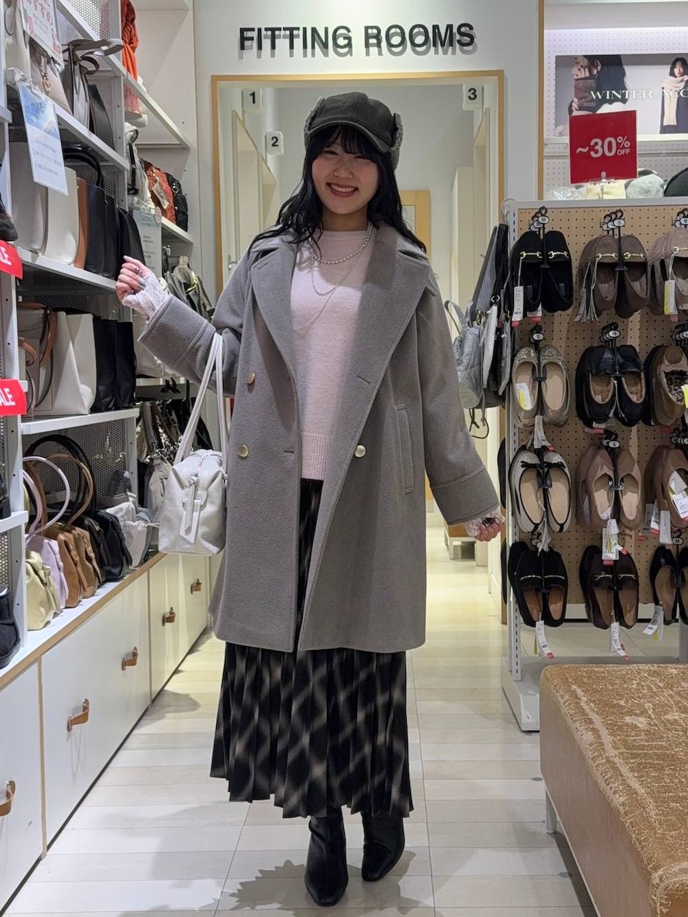 パープル系のボストンバッグ、ベージュ系のチェスターコート、ピンク系のニット/セーターを着用したレディースの冬コーディネートの4枚目の写真