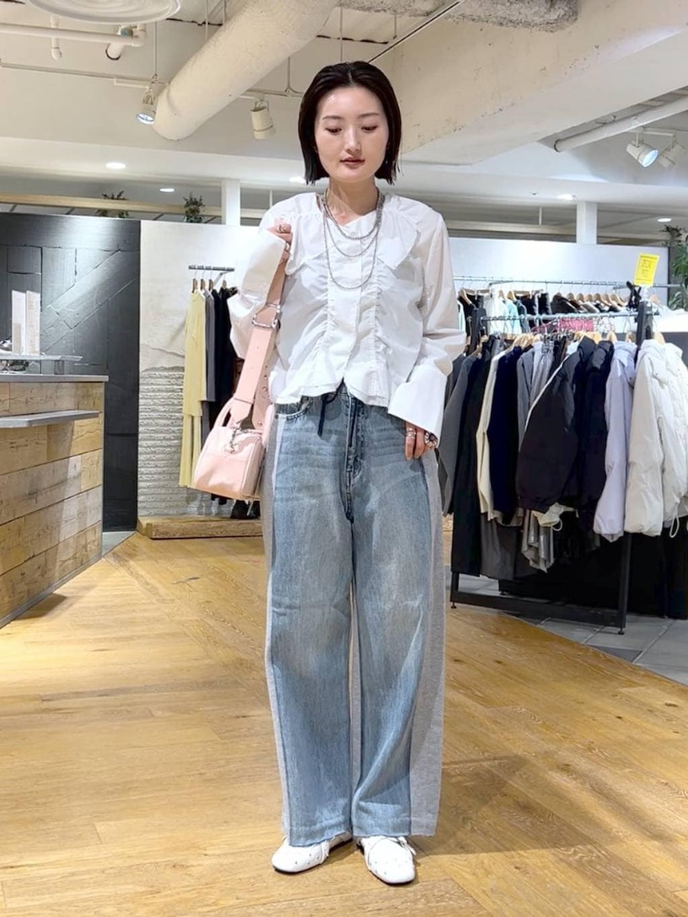 ピンク系のボストンバッグ、ブルー系のデニムパンツ、ホワイト系のドレスシューズを着用したレディースの冬コーディネートの2枚目の写真