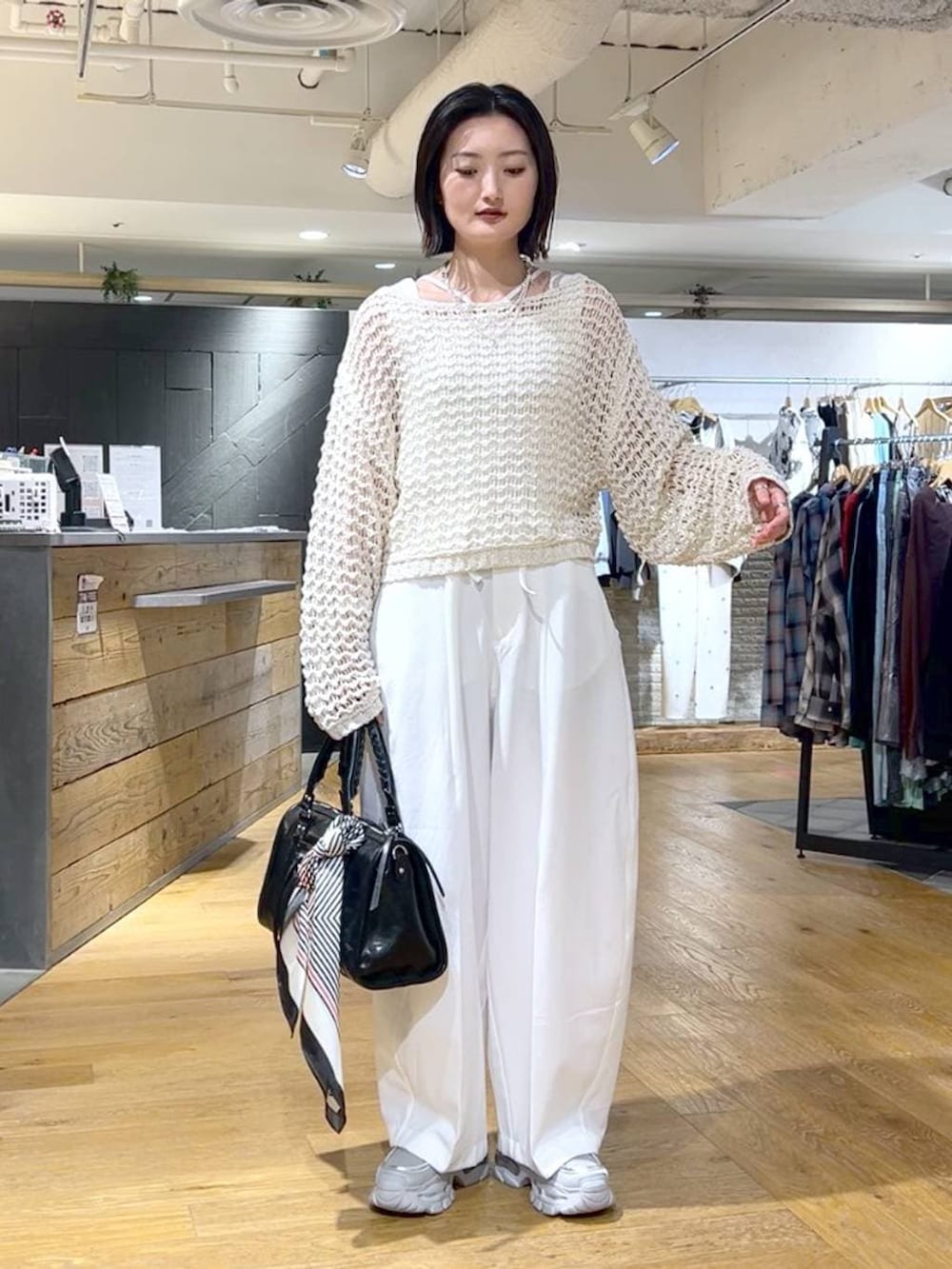 シルバー系のローファー、ブラック系のボストンバッグ、ホワイト系のニット/セーターを着用したレディースの春コーディネートの3枚目の写真