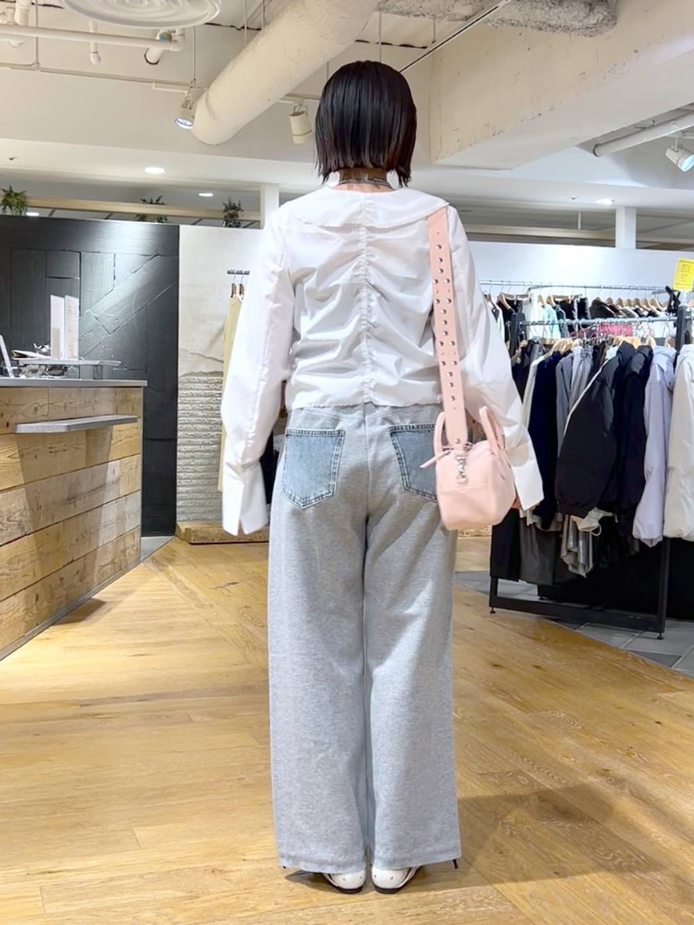 ピンク系のボストンバッグ、ブルー系のデニムパンツ、ホワイト系のドレスシューズを着用したレディースの冬コーディネートの5枚目の写真