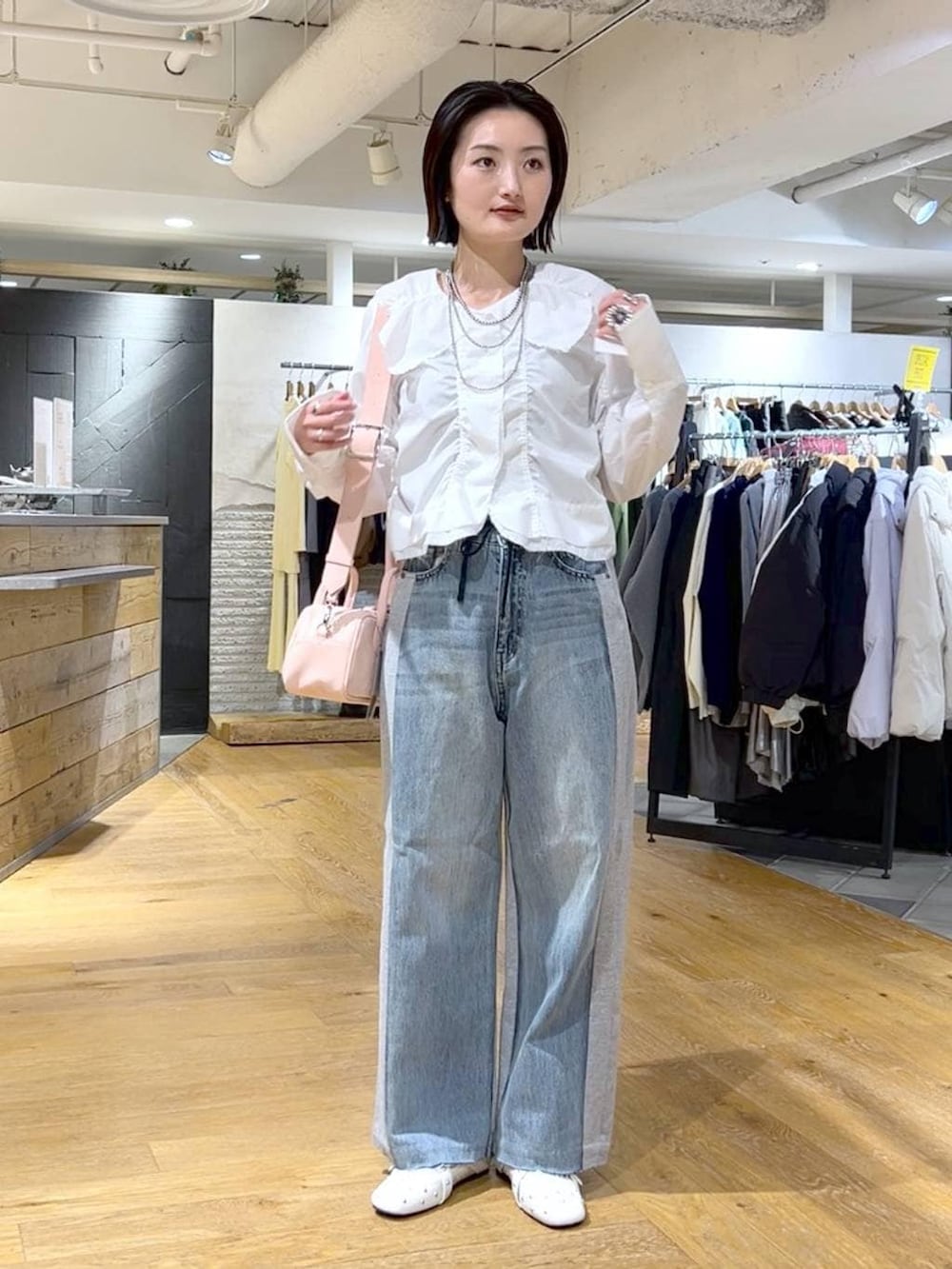 ピンク系のボストンバッグ、ブルー系のデニムパンツ、ホワイト系のドレスシューズを着用したレディースの冬コーディネートの3枚目の写真