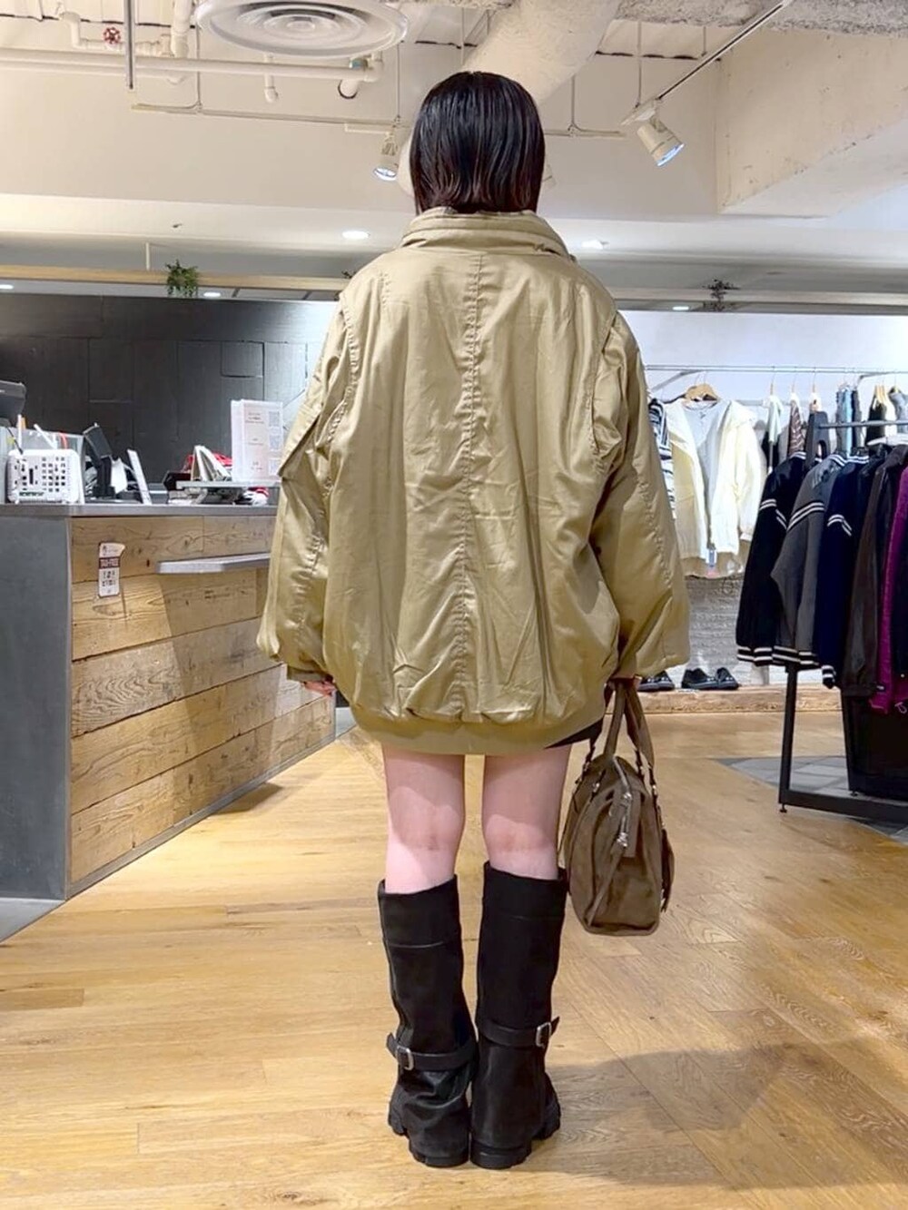 ブラウン系のボストンバッグ、ブラック系のブーツ、ブラック系のその他パンツを着用したレディースの冬コーディネートの6枚目の写真