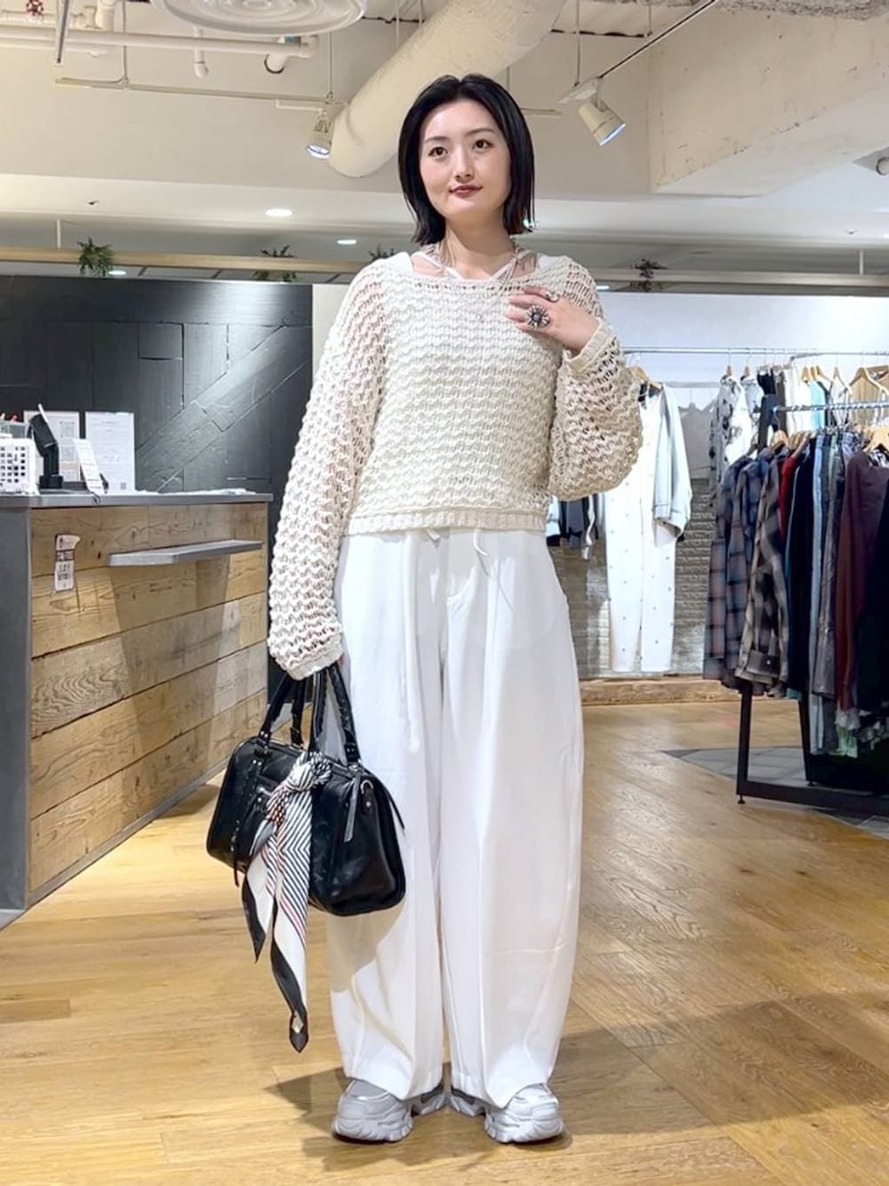 シルバー系のローファー、ブラック系のボストンバッグ、ホワイト系のニット/セーターを着用したレディースの春コーディネートの2枚目の写真