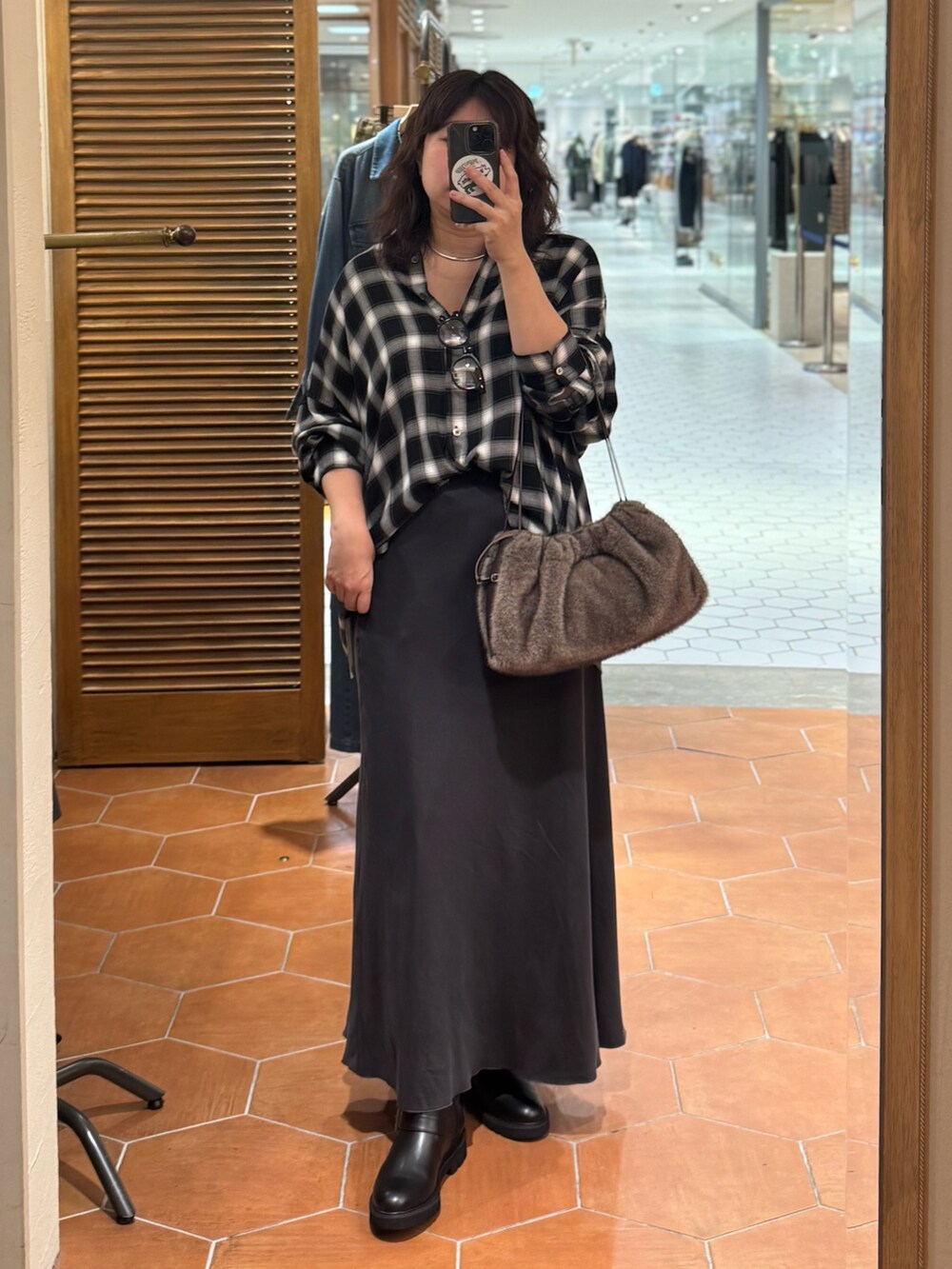 ブラウン系のハンドバッグ、グレー系のスカート、ブラック系のブーツを着用したレディースの秋コーディネートの2枚目の写真