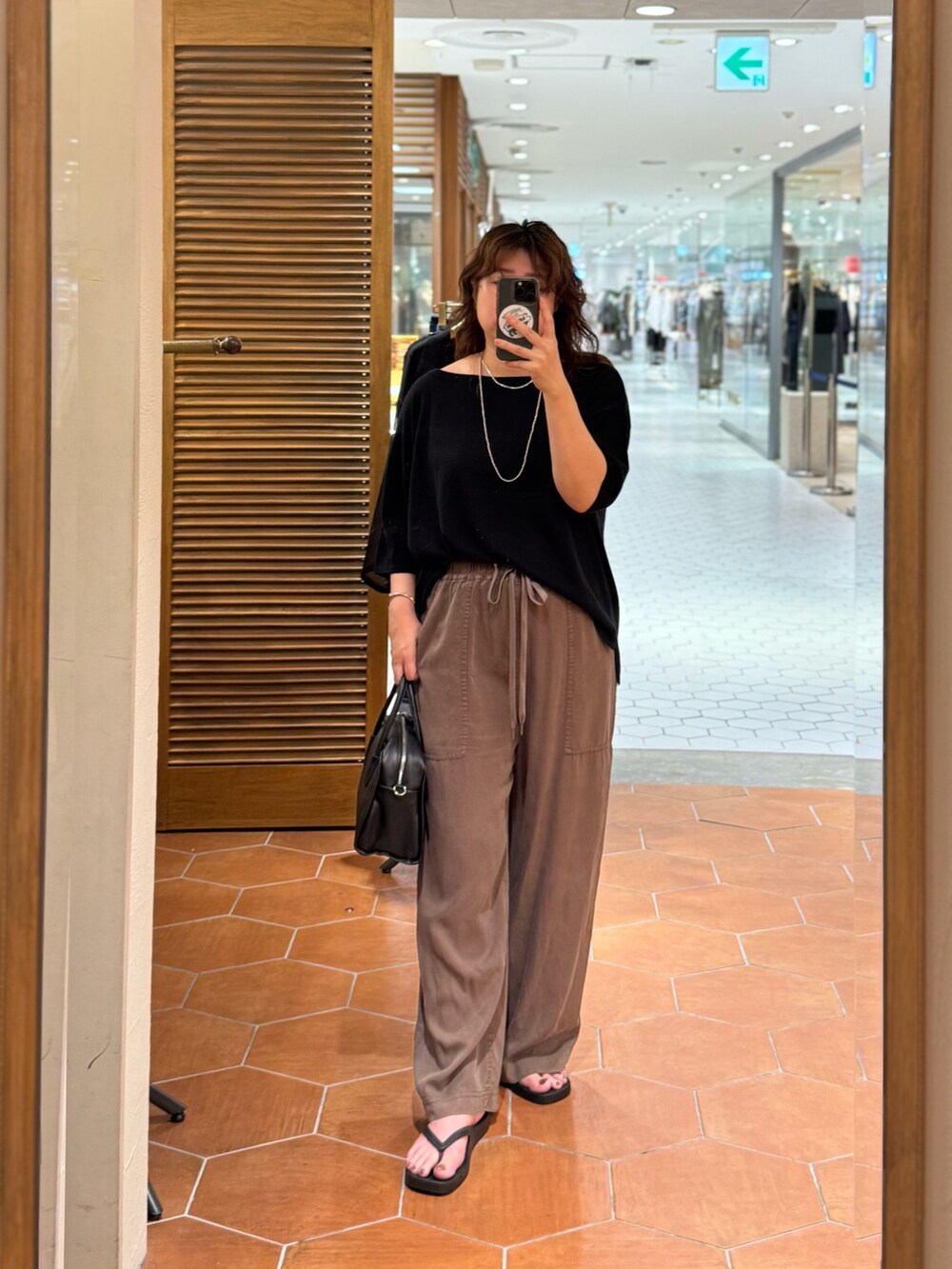 ブラック系のボストンバッグ、ブラック系のニット/セーター、ブラウン系のその他パンツを着用したレディースの夏コーディネートの3枚目の写真