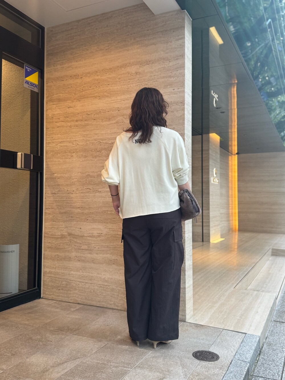 ブラウン系のカーゴパンツ、ブラウン系のハンドバッグ、ベージュ系のパンプスを着用したレディースの夏コーディネートの2枚目の写真