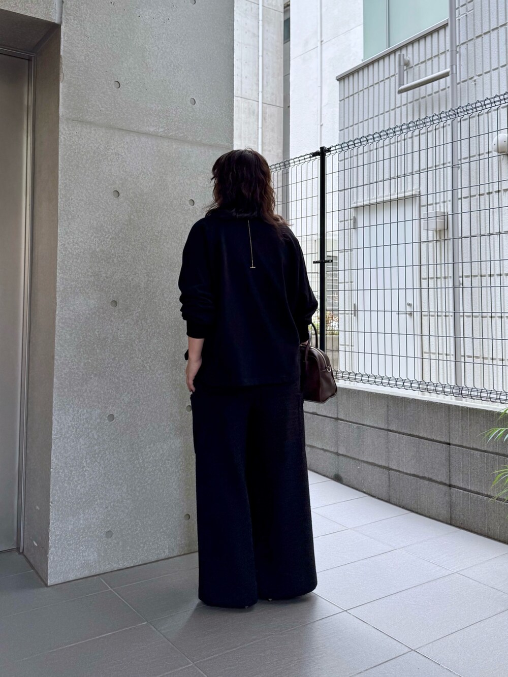 ブラウン系のボストンバッグ、ブラック系のその他パンツ、ブラック系のスウェットを着用したレディースの夏コーディネートの3枚目の写真