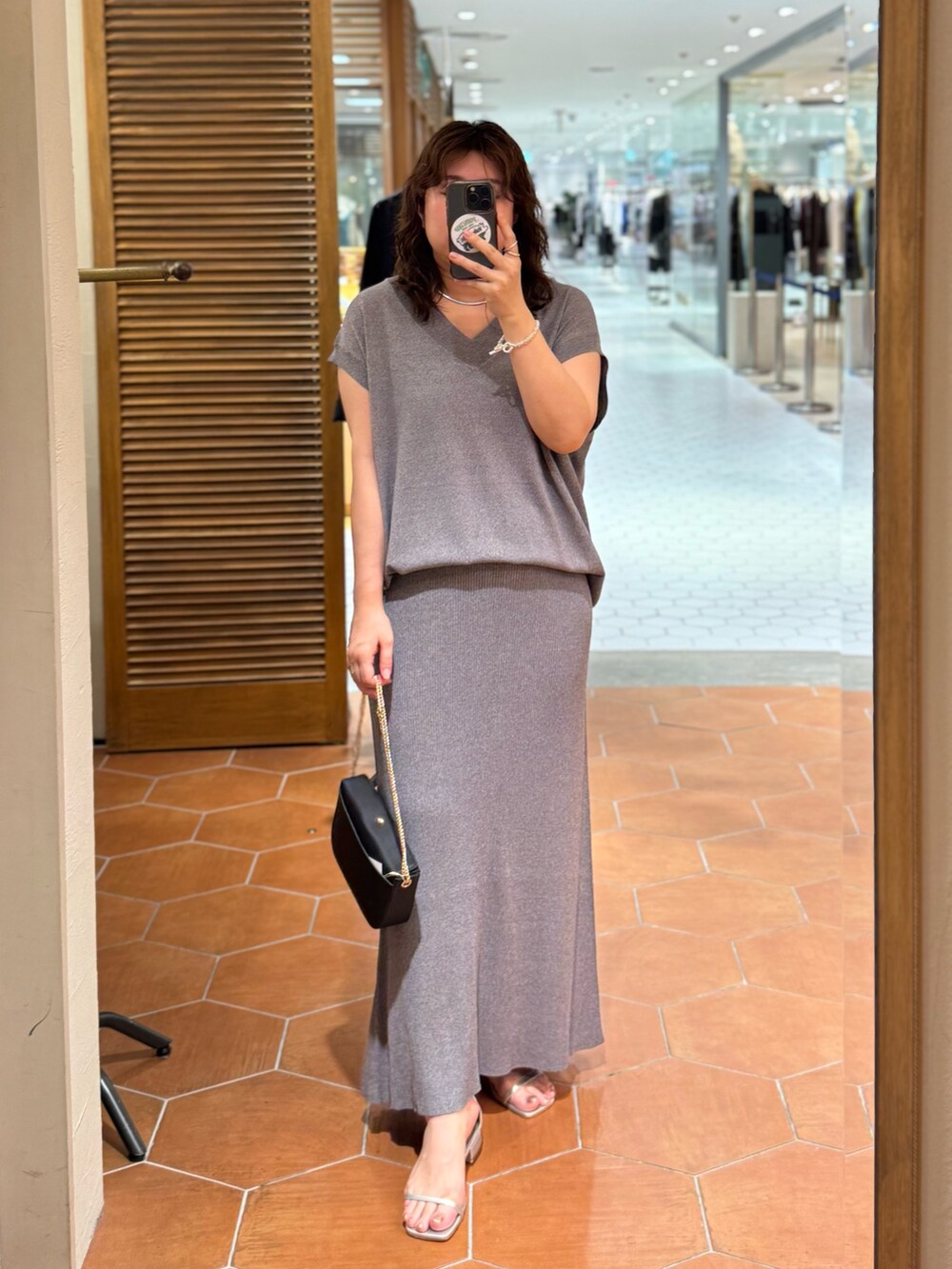 グレー系のニット/セーター、ブルー系のシャツ/ブラウス、グレー系のスカートを着用したレディースの夏コーディネートの2枚目の写真