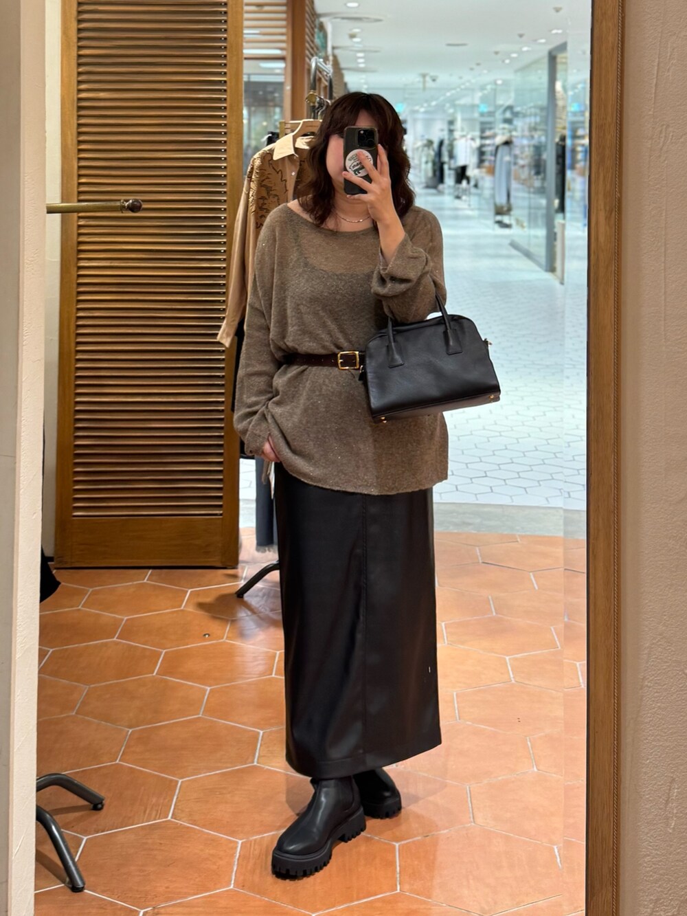 ブラック系のスカート、ブラック系のボストンバッグ、ブラック系のブーツを着用したレディースの秋コーディネートの3枚目の写真